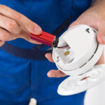 man putting in batteries to a smoke detector